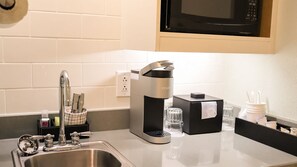 Eine Küche mit einer Keurig-Kaffeemaschine, einem Spülbecken und einer Mikrowelle.