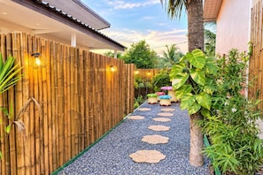 A bamboo fence, a pathway with stepping stones, and a variety of plants. - Fahsai Pool House (Koh Lanta)