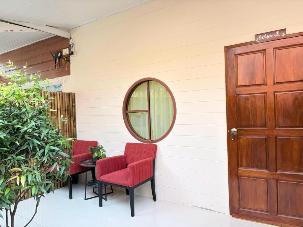 A room with a wooden door, a round window, and two red chairs.