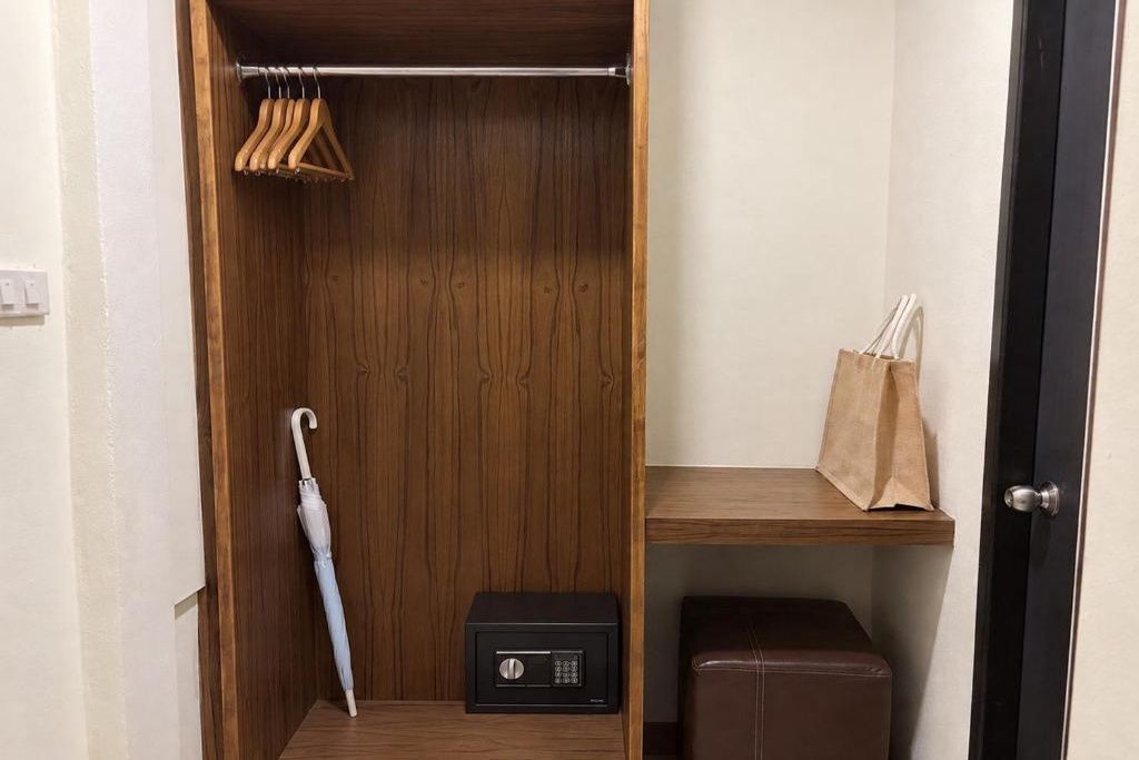 A walk-in closet with a hanging rack, a suitcase, and a small shelf with a bag.