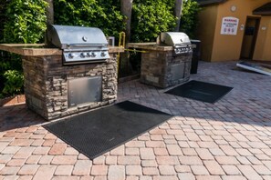 Un área de barbacoa al aire libre con estaciones de parrilla de piedra y un letrero de advertencia en la pared.