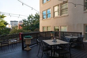 Eine Terrasse mit Sitzgelegenheiten im Freien, Lichterketten und einem Feuerlöscher.