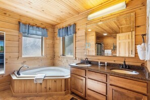 A wooden cabin bathroom with a large bathtub, two sinks, and a mirror. - Branson | Family Treehouse Retreat | Pools + Fitness | 2BR (Ridgedale)
