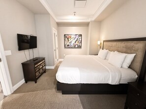 Un dormitorio con cama, cómoda, televisor y un cuadro en la pared.