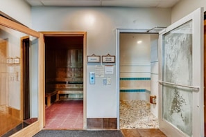 En hall som leder till en bastu och ett ångbad, med kakelgolv och en träbänk.