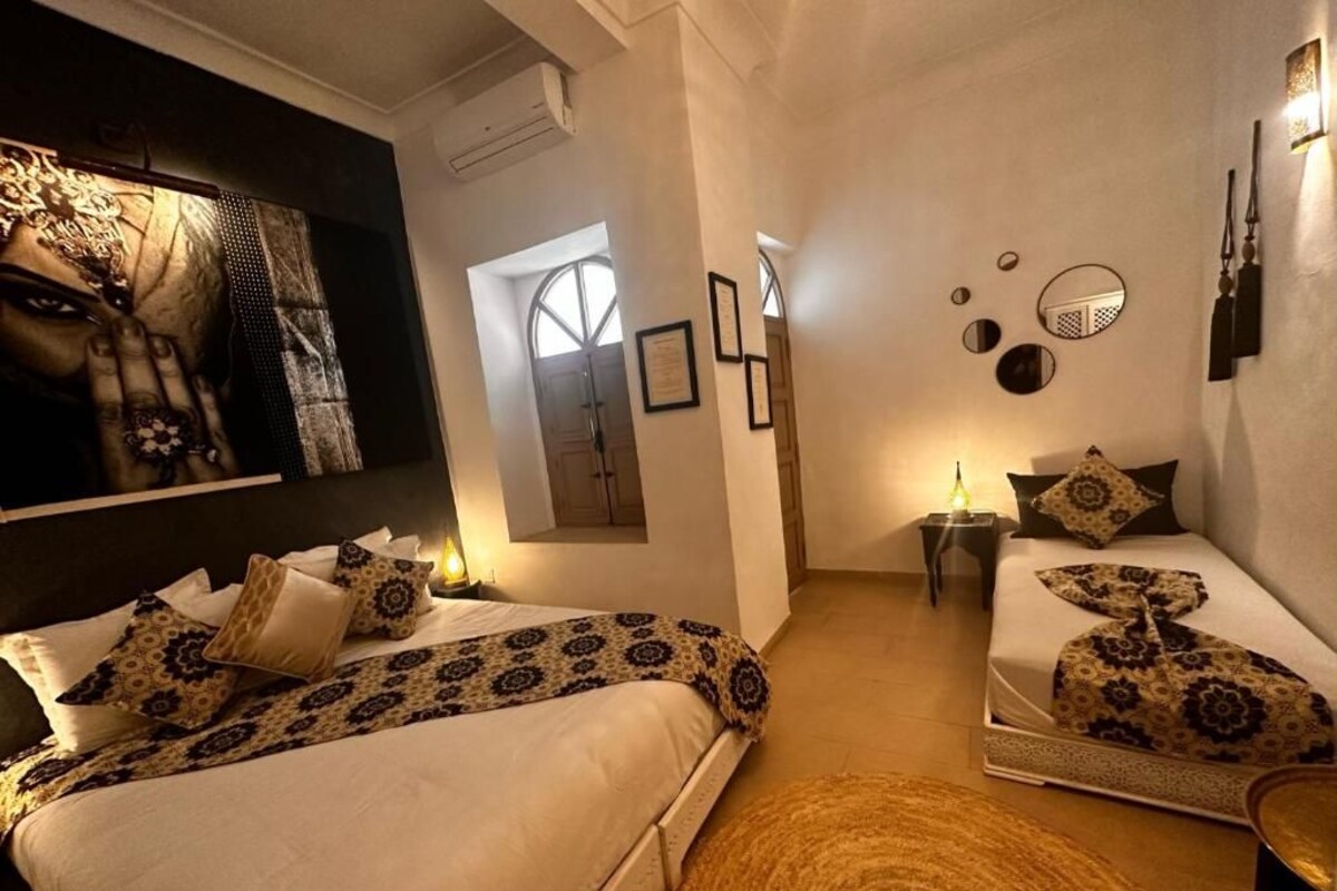 A hotel room with two beds, a large mirror, wall-mounted lights, and a rug.