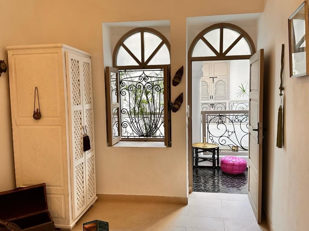 A hallway with a white cabinet, a decorative window, and a glimpse of a kitchen area.