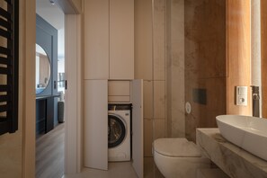 Un baño pequeño con lavadora integrada, inodoro y lavamanos.