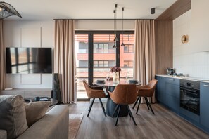 Una cocina moderna con comedor, un televisor de pantalla plana y un amplio ventanal con cortinas.