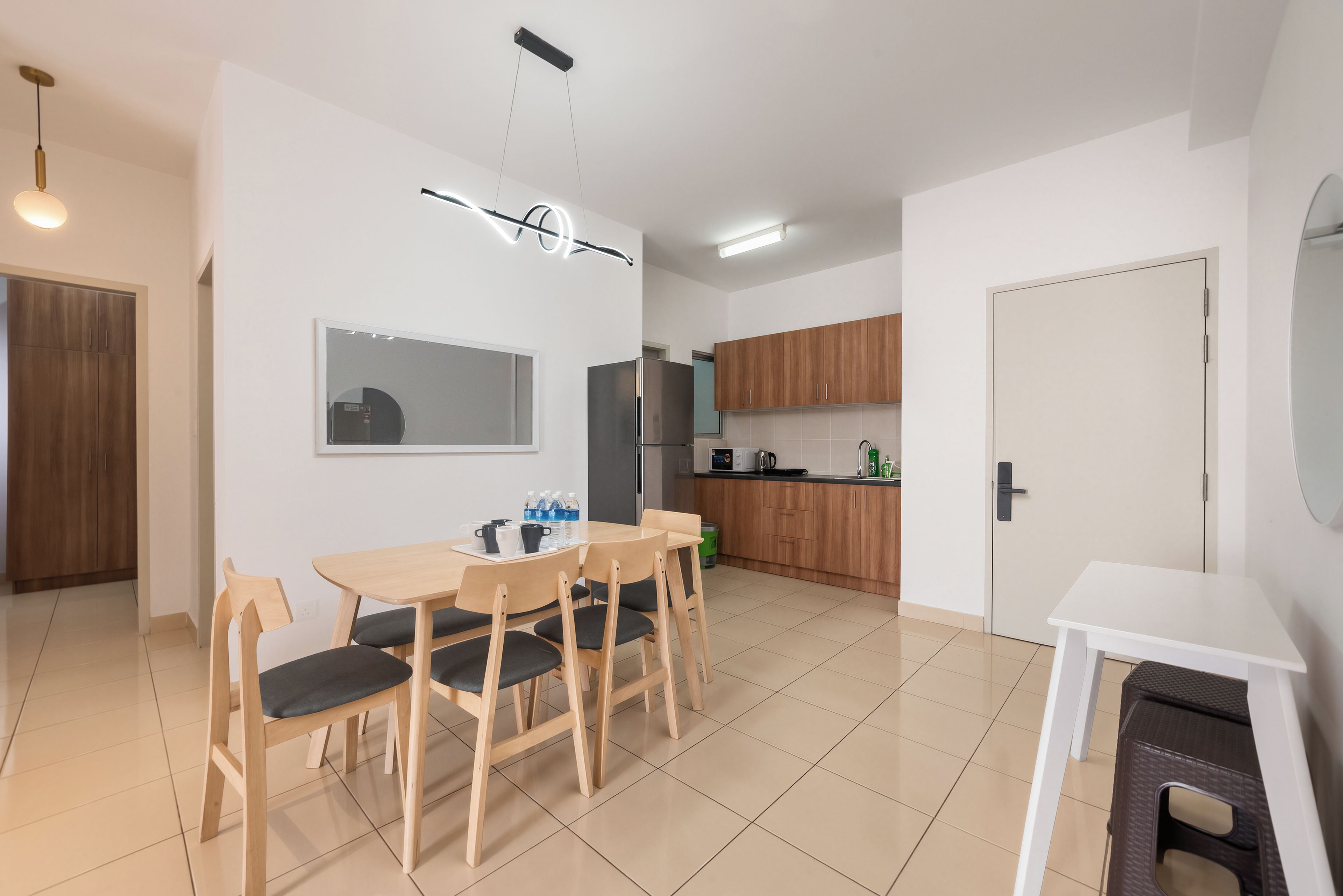 Une cuisine moderne avec des meubles en bois, un réfrigérateur et un coin repas comprenant une table et des chaises.