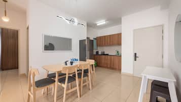 Une cuisine moderne avec des meubles en bois, un réfrigérateur et un coin repas comprenant une table et des chaises.