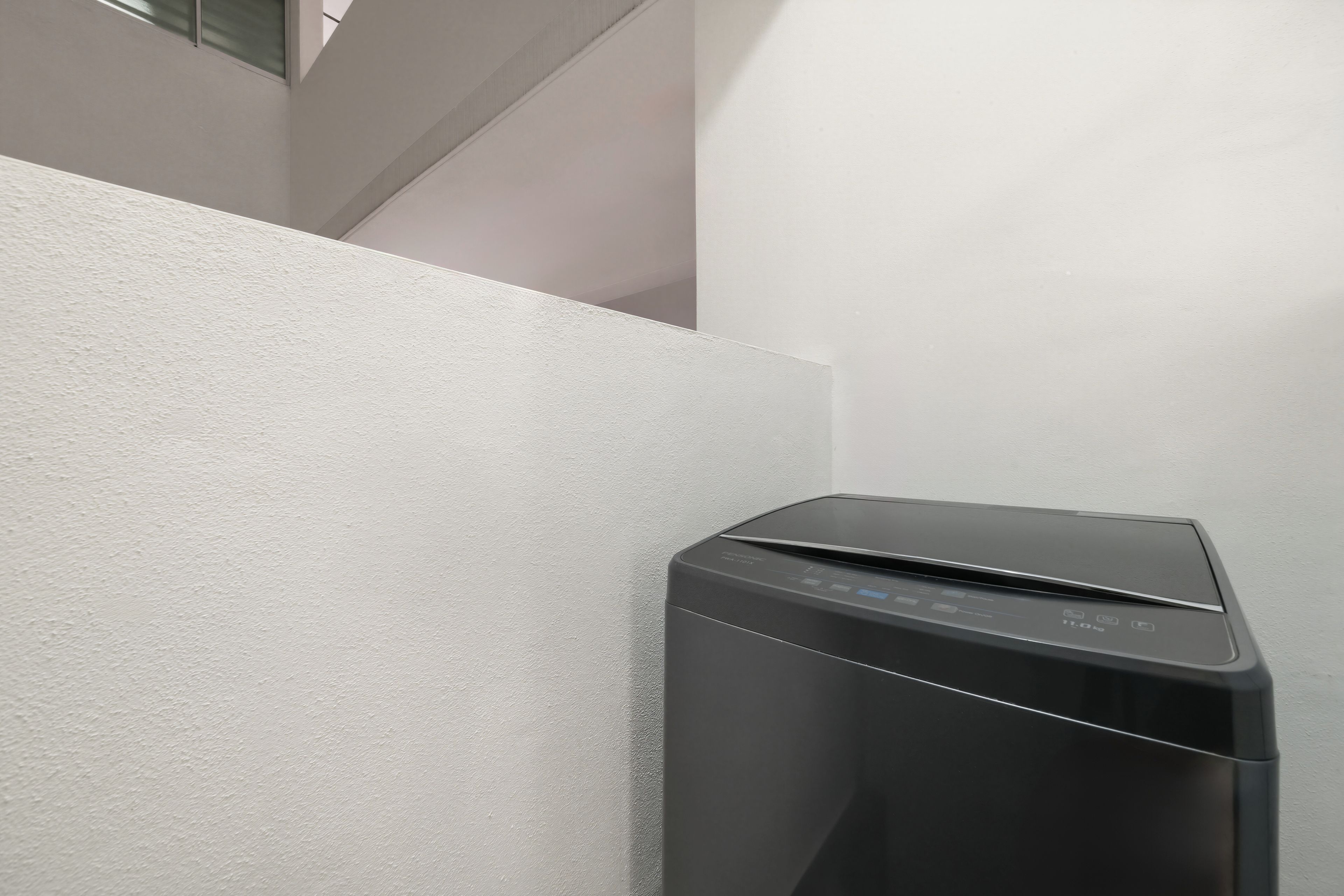 A black, modern-looking device, possibly a printer or copier, placed against a white wall in a corner.