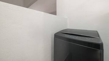 A black, modern-looking device, possibly a printer or copier, placed against a white wall in a corner.
