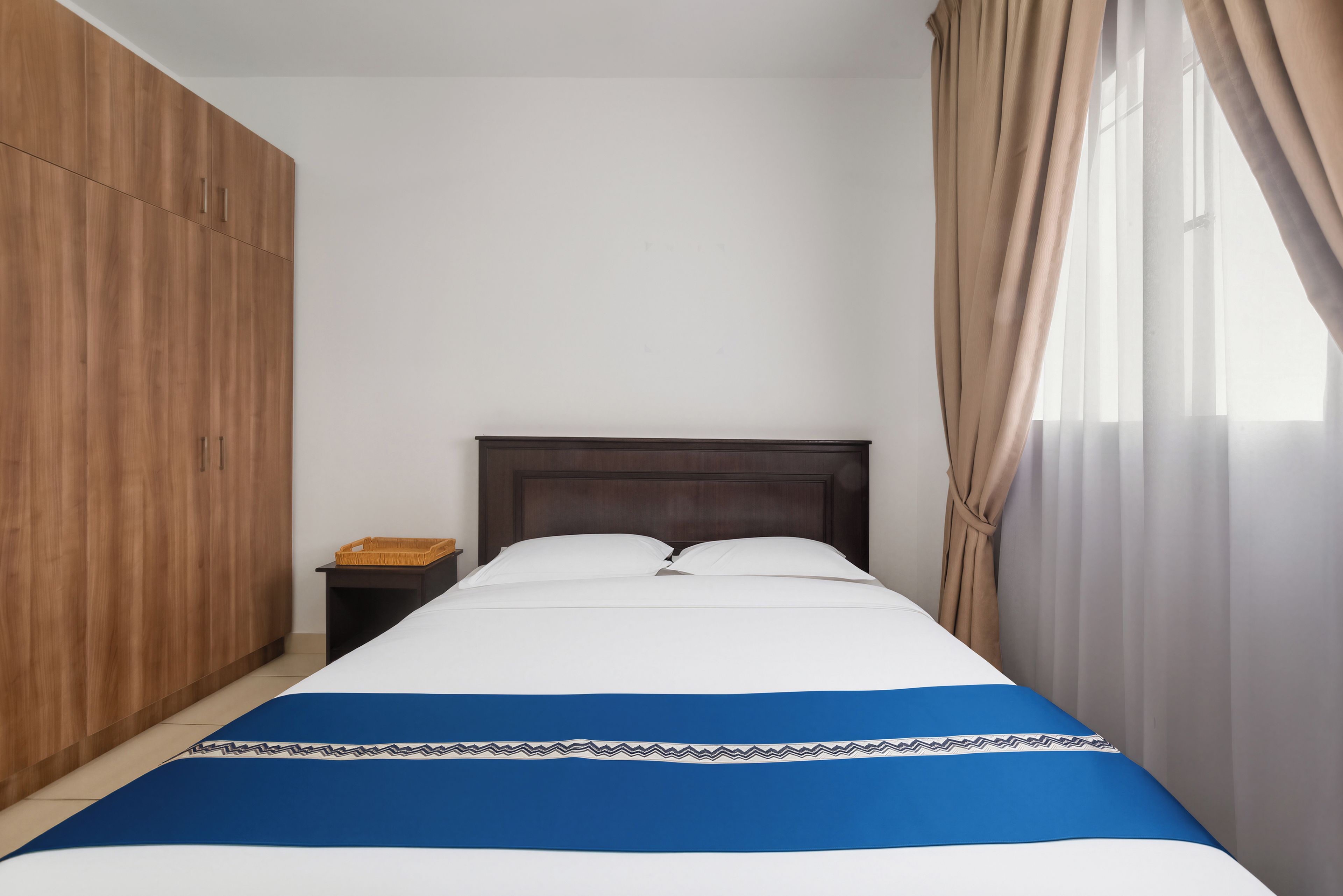 A bedroom with a bed, wooden wardrobe, and a nightstand.