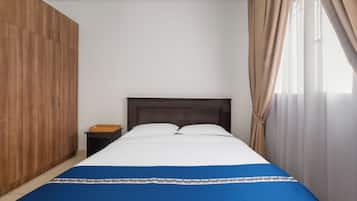 A bedroom with a bed, wooden wardrobe, and a nightstand.