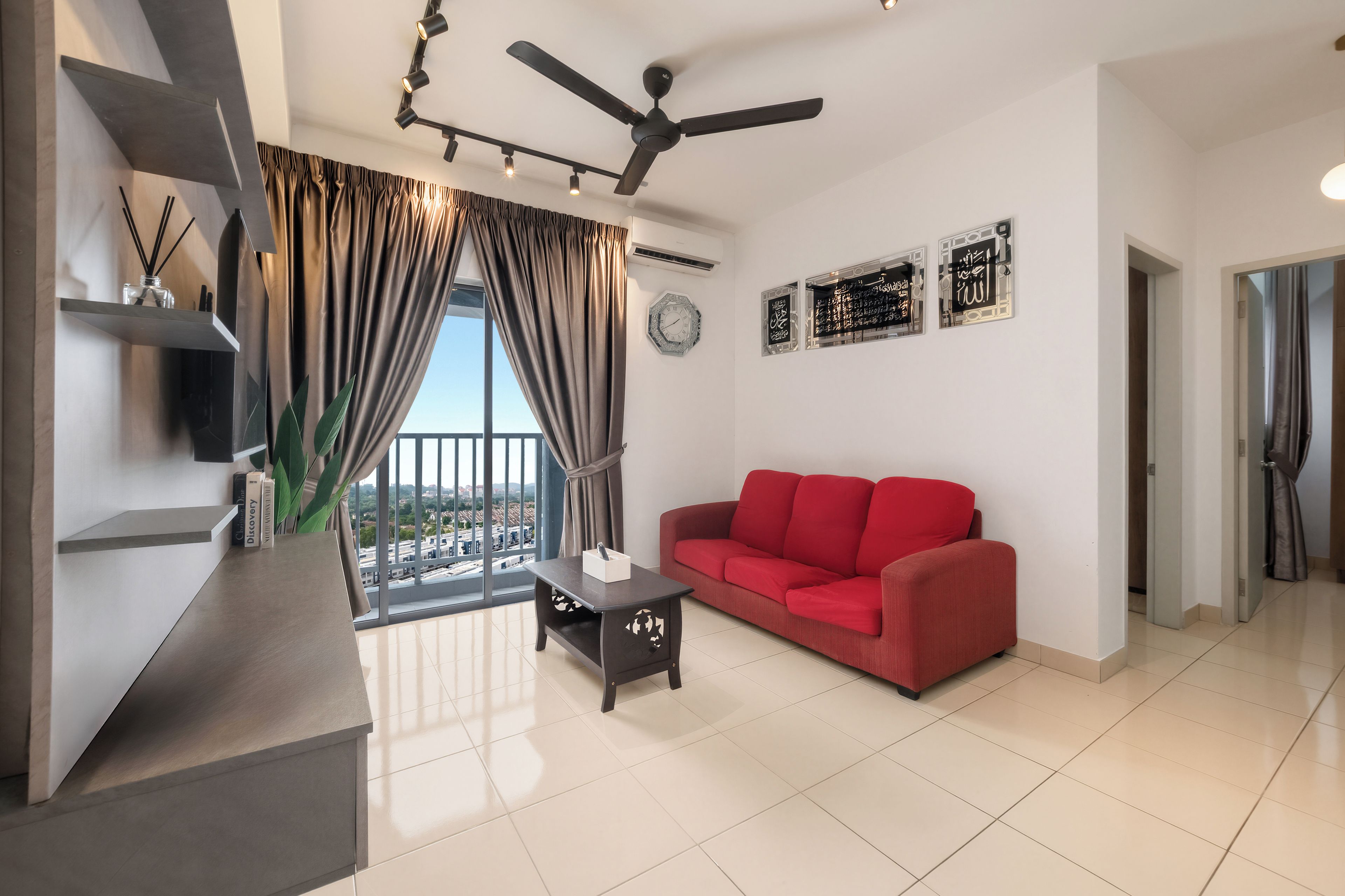 Un salon moderne avec un canapé rouge, un ventilateur de plafond et une vue dégagée grâce à de grandes fenêtres.