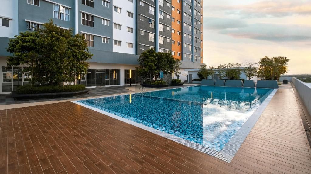 Piscina en la azotea con vistas a un edificio de varios pisos, rodeada de árboles y una terraza de madera.
