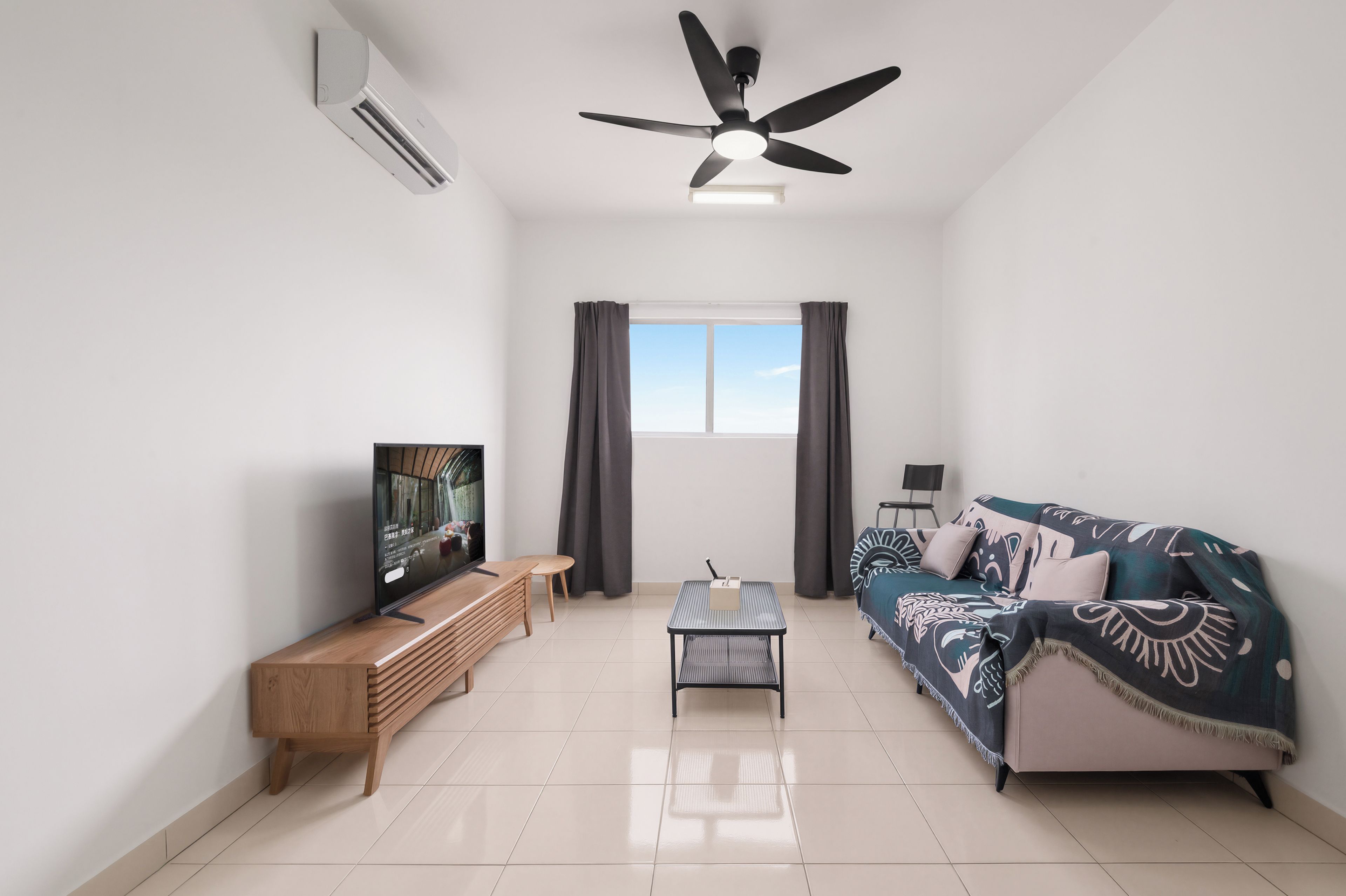 Una sala de estar moderna con una televisión de pantalla plana, un ventilador de techo, un sofá y una mesa de centro.