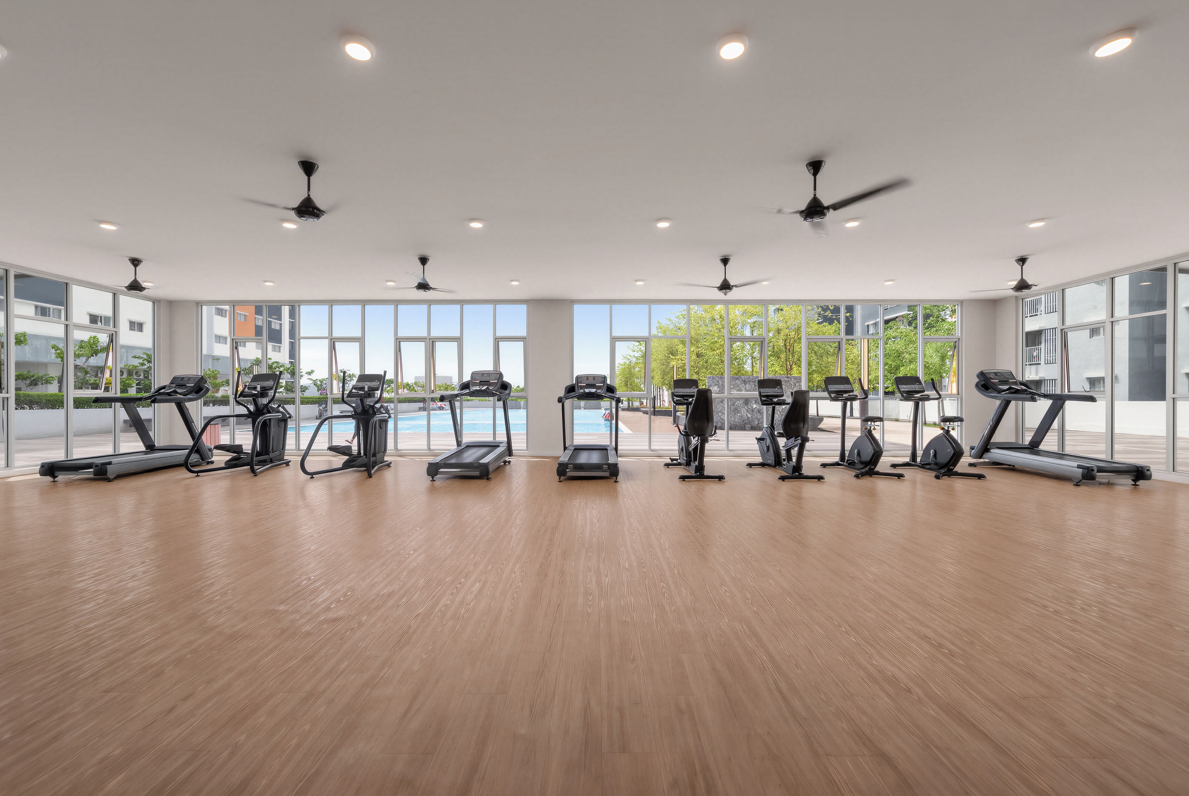 A spacious indoor gym with multiple treadmills, stationary bikes, and ceiling fans.
