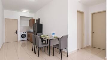 Una cocina funcional con lavadora, refrigerador y comedor con mesa y sillas.