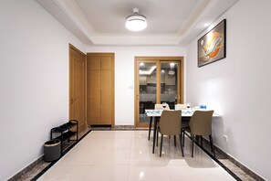 Un comedor con una mesa lista para dos, un cubo de basura y un zapatero.