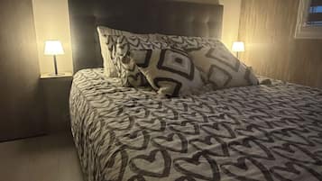 A bedroom with a patterned bedspread, two bedside lamps, and a wooden headboard.