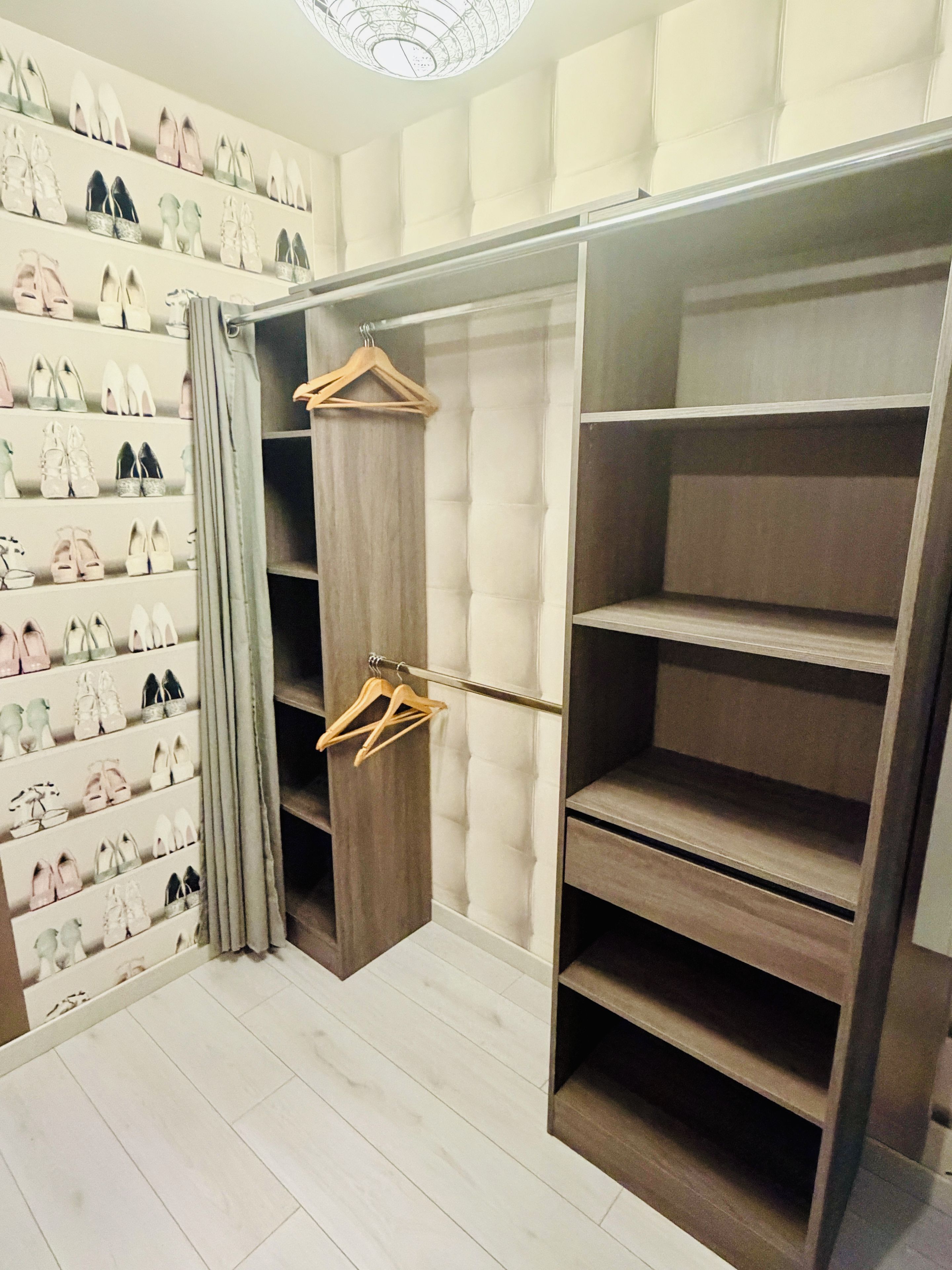 A walk-in closet with multiple shelves and hanging space for shoes.