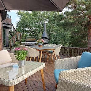 Una terrazza esterna con mobili in vimini, un barbecue e un camino.