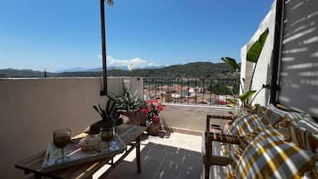 A balcony with a table, chairs, and potted plants.