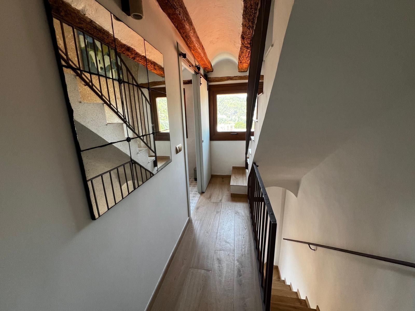 A narrow hallway with a wooden staircase and a metal railing.
