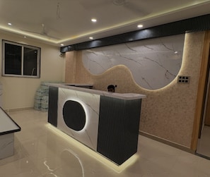 Un mostrador de recepción con una pared de mármol y diseño moderno.