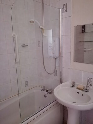 Un baño moderno con ducha de vidrio, un lavabo blanco y un espejo sobre él.