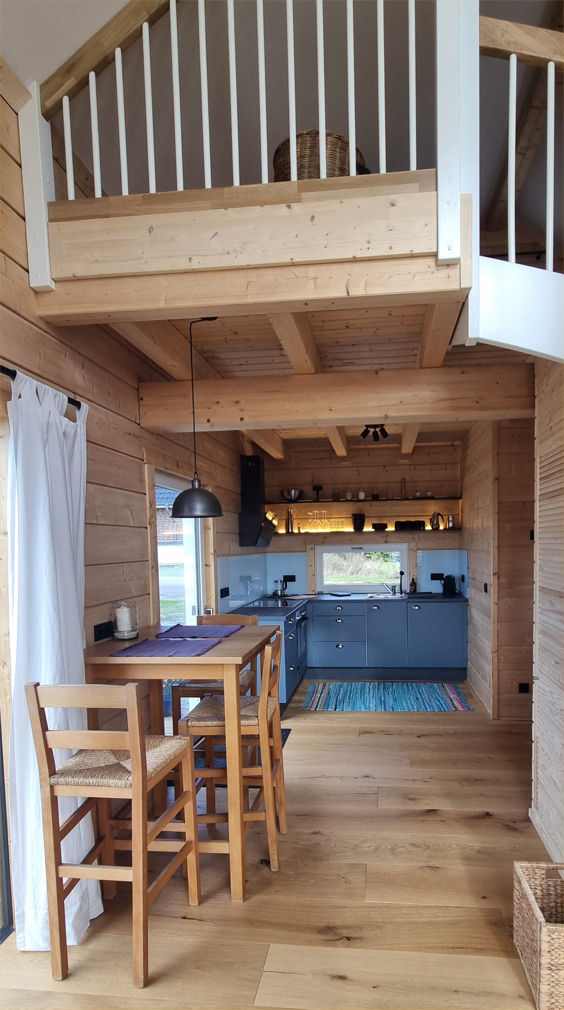 Ein Holzinnenraum mit Essbereich, Küche und einem Schlafbereich/Loft.