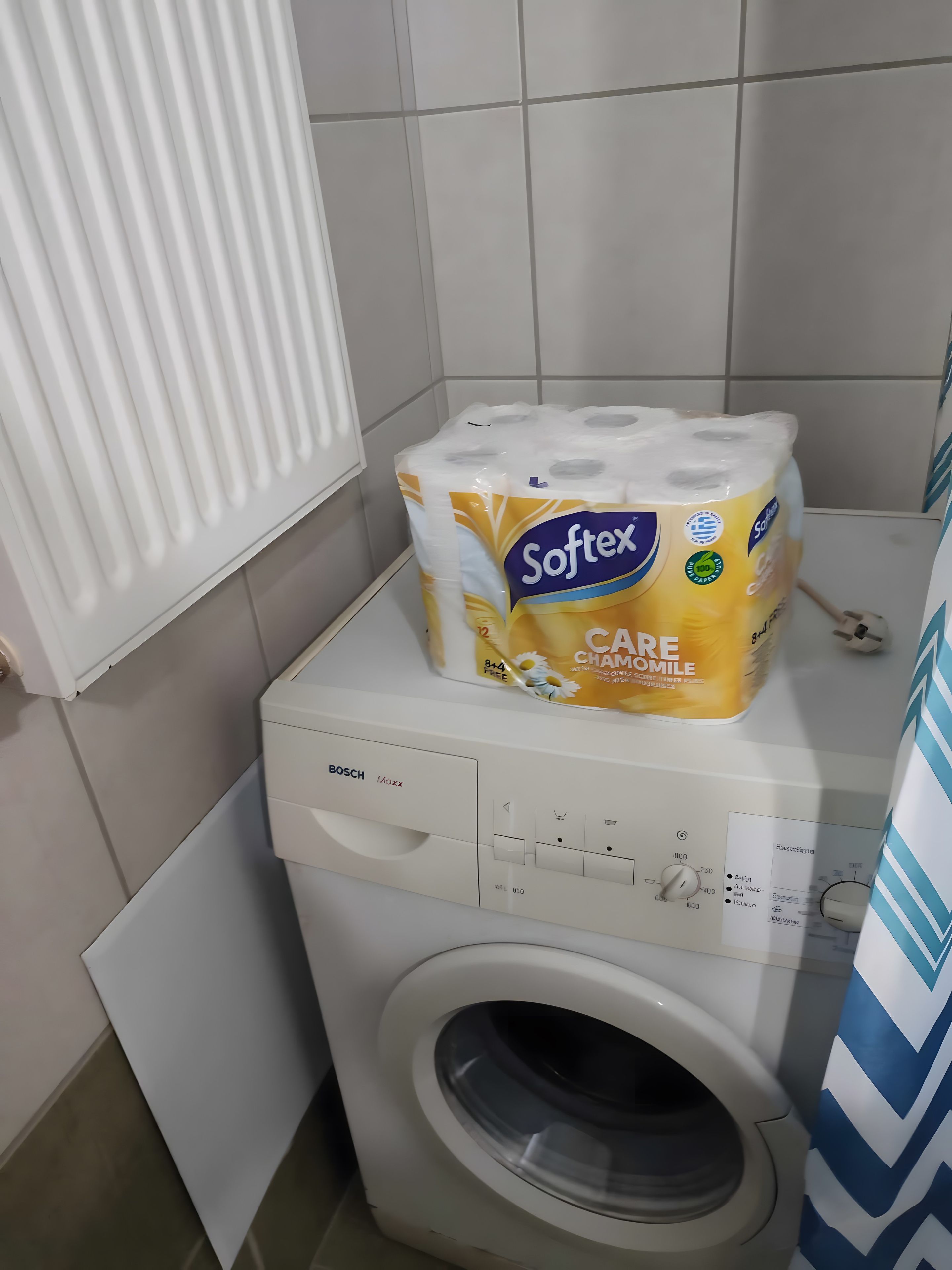 A Bosch washing machine with a package of Softex toilet paper on top.