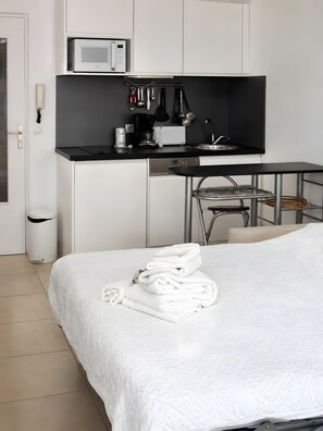 Une chambre d’hôtel comprenant un lit, une petite kitchenette équipée d’un four à micro-ondes, d’une machine à café et d’un évier.