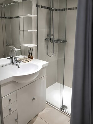 Une salle de bain moderne avec une douche à parois de verre, un lavabo blanc et un miroir.