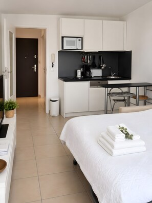 Una habitación de hotel moderna con cama, kitchenette, escritorio y baño.