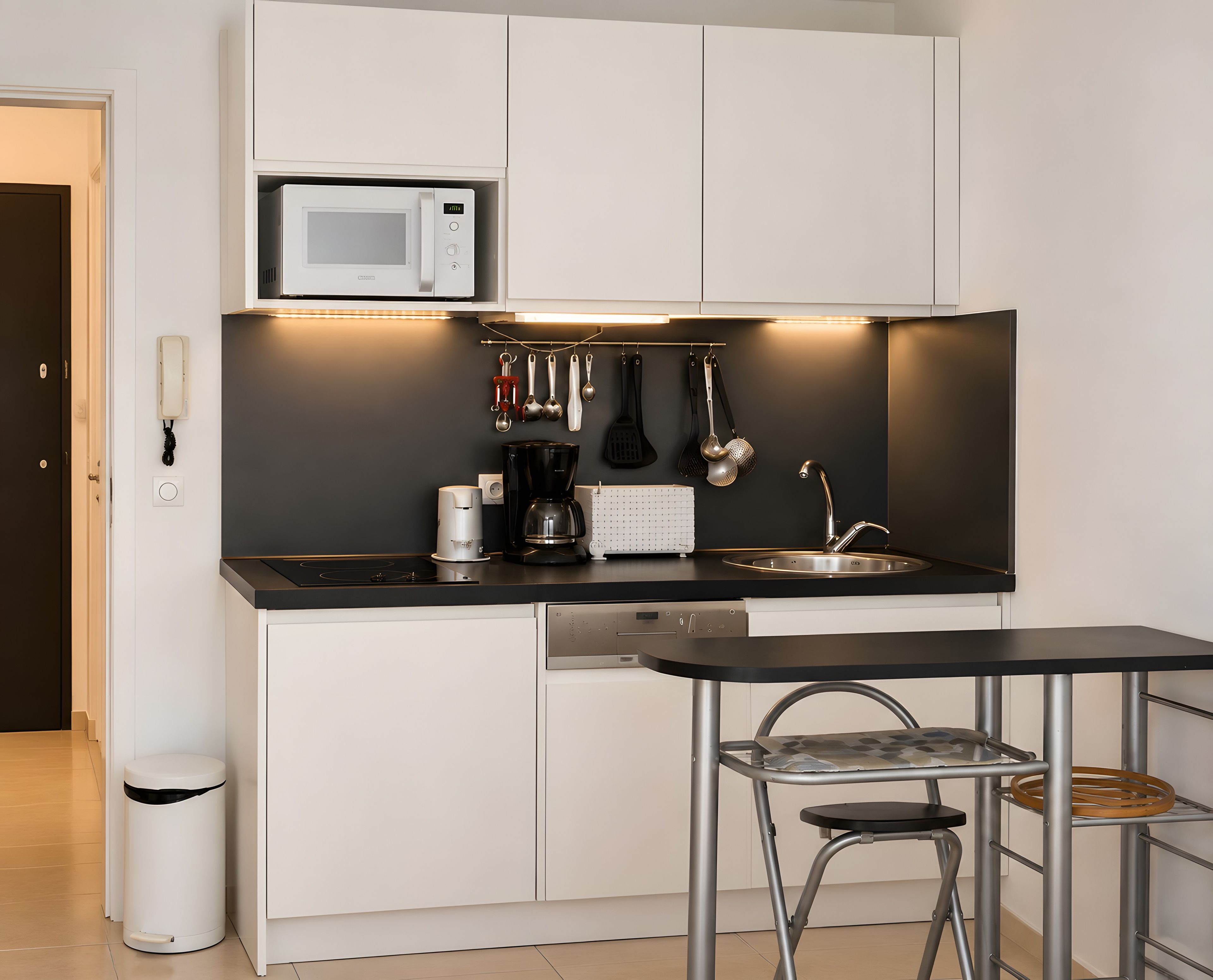 A compact kitchen with a microwave, coffee maker, and a sink.