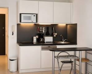 Cocina compacta con microondas, cafetera y pileta.