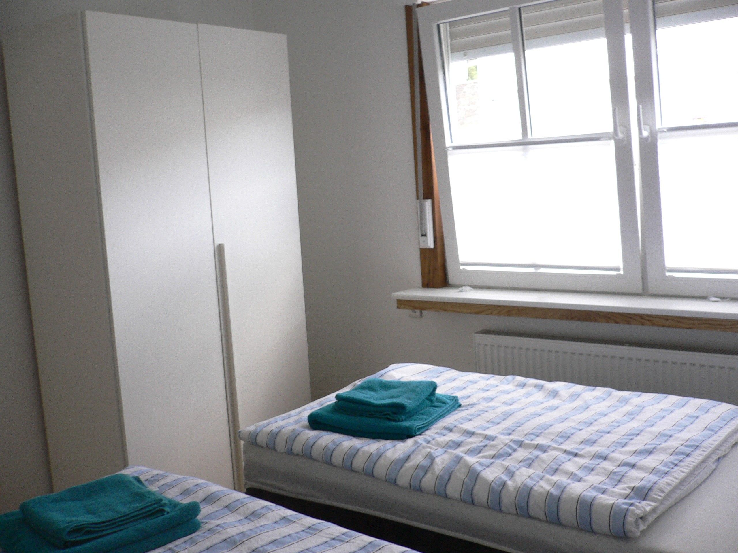 A bedroom with a bed, a wardrobe, and a window.