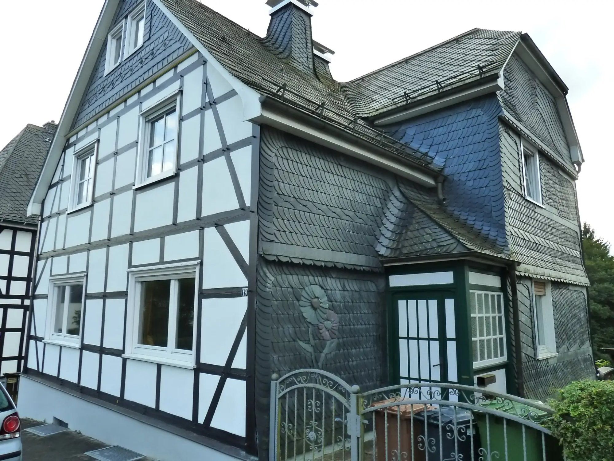 Ein traditionelles Fachwerkhäuschen mit einem steilen Satteldach, zahlreichen Fenstern und einem verschlossenen Eingang.