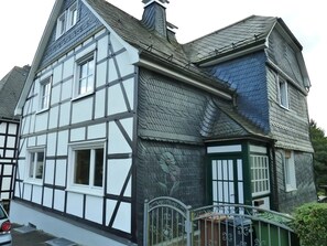 Ein traditionelles Fachwerkhäuschen mit einem steilen Satteldach, zahlreichen Fenstern und einem verschlossenen Eingang.