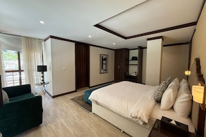 A modern bedroom with a large bed, a green sofa, a bedside table, and a window with curtains. - The Sarai Hotel & Resorts (Naran)