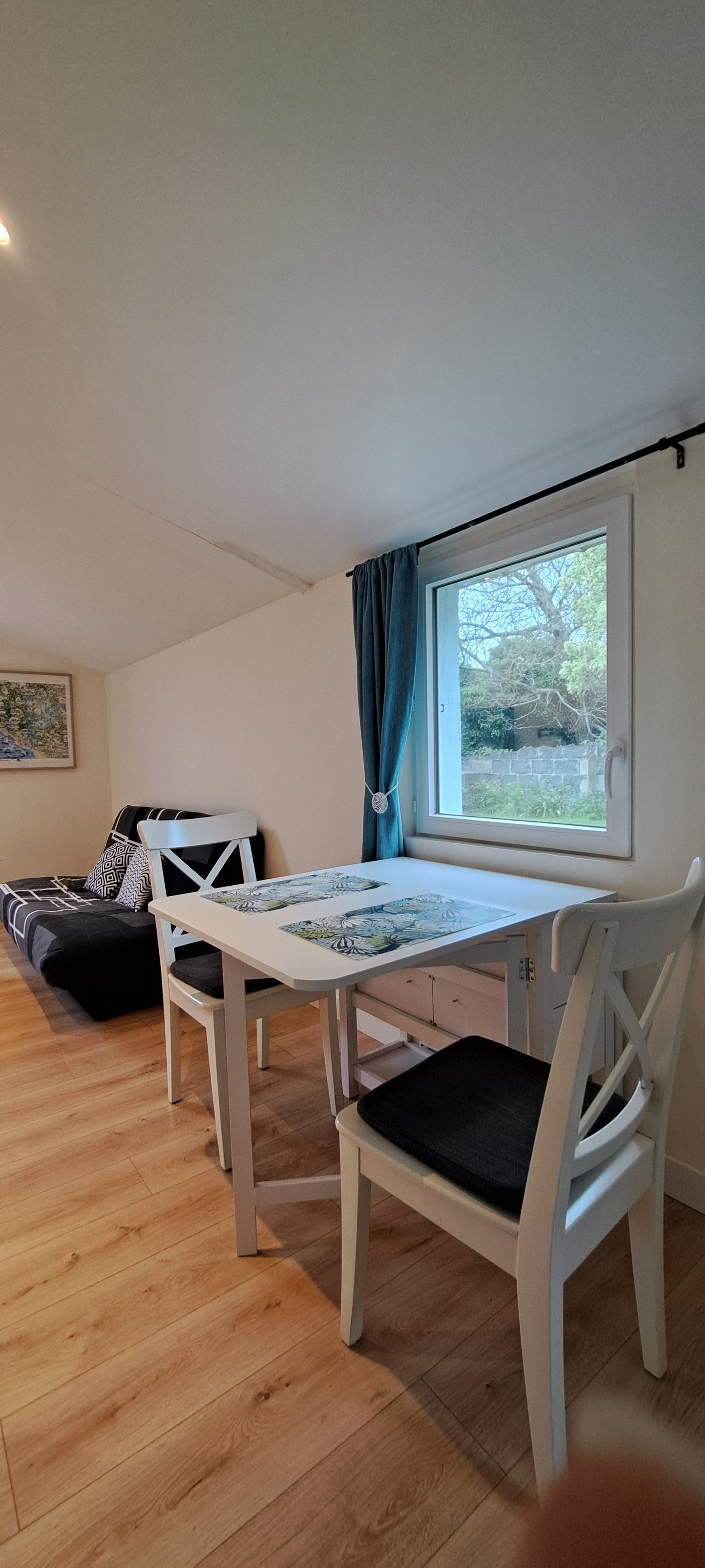 Et værelse med spisebord, stole, en sofa og et vindue med gardiner.