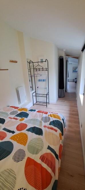 A bedroom with a bed, a metal drying rack, a radiator, and a hallway leading to another room. - Holiday Home 'Ty Melen' with Shared Terrace, Shared Garden and Wi-Fi (Locmiquélic)