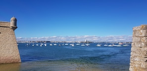 A harbor with boats, a stone wall, and a clear blue sky.
