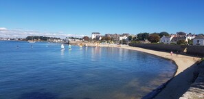 A coastal town with a sandy beach, calm water, and buildings along the shore. - Holiday Home 'Ty Melen' with Shared Terrace, Shared Garden and Wi-Fi (Locmiquélic)