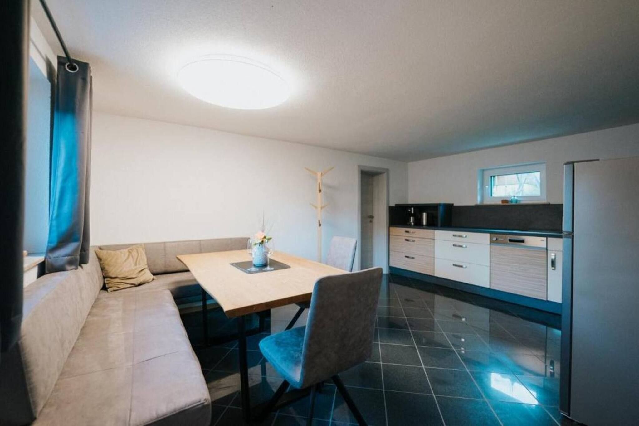 A compact living space with a kitchenette, a dining area with a table and chairs, and a sofa.