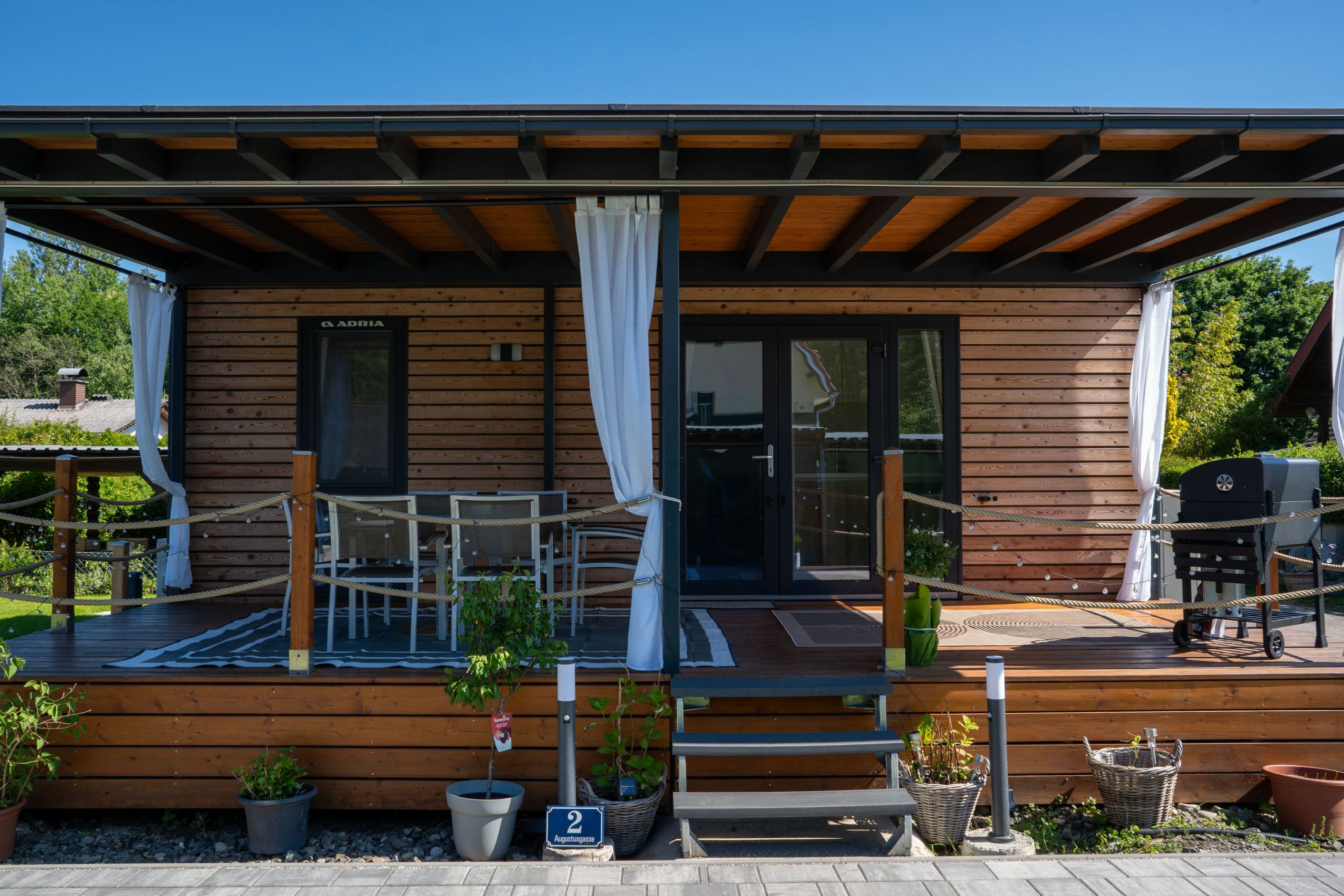 Una cabana de fusta amb un porxo cobert, seients exteriors i una zona de barbacoa.