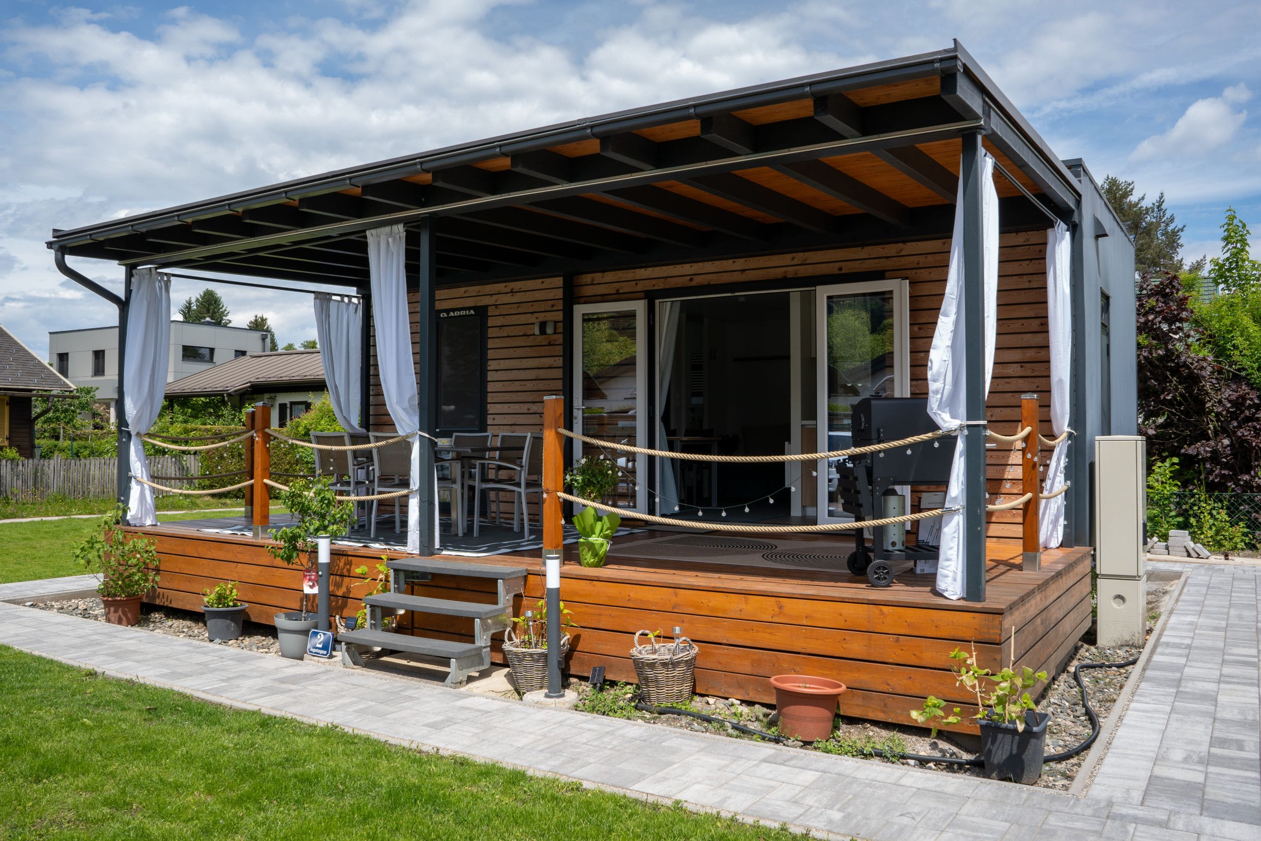 A wooden cabin with a covered porch, outdoor seating, and potted plants.